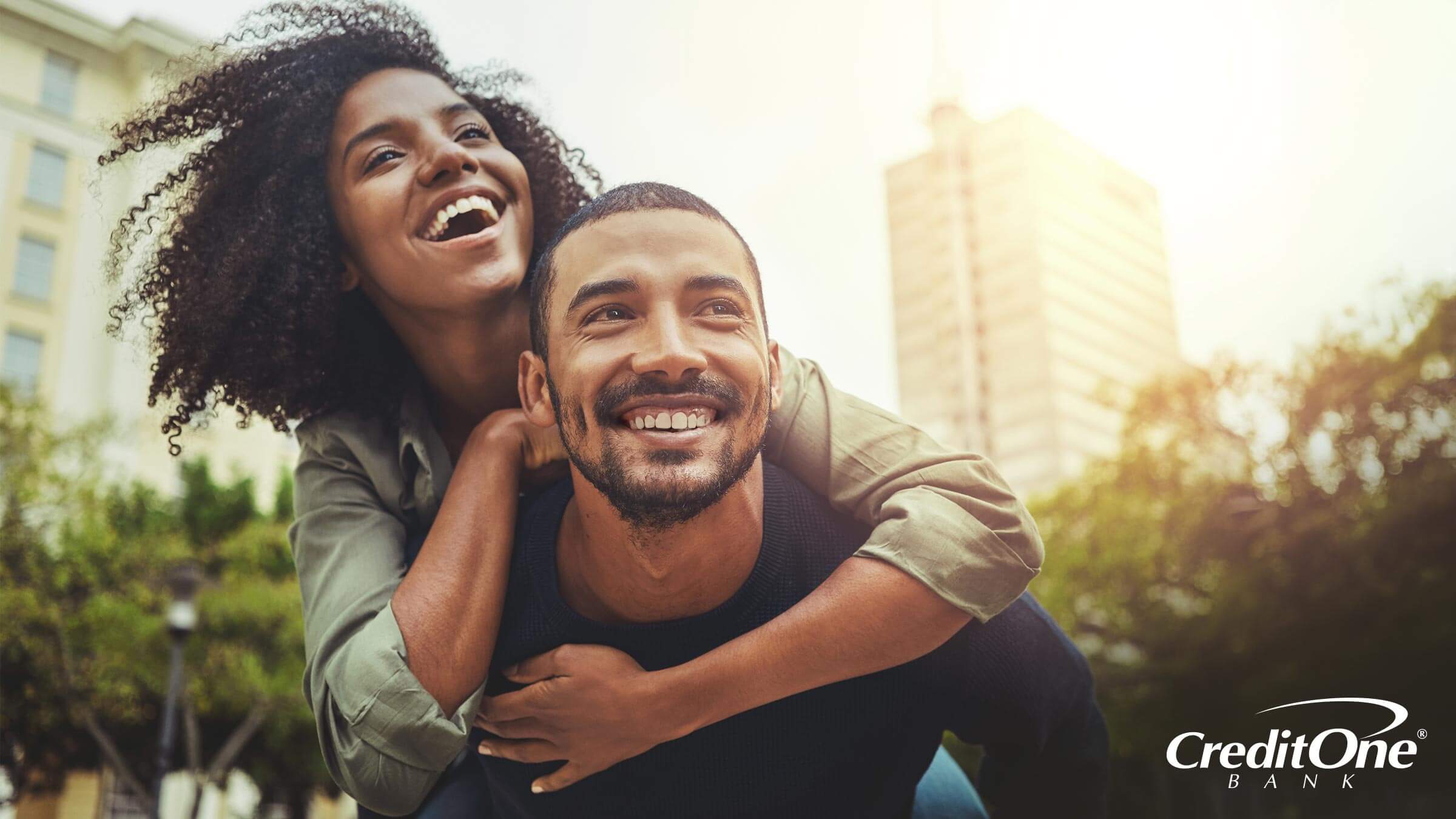 A young man gives his wife a piggyback ride, representing how she could improve her credit by piggybacking on his credit card account.