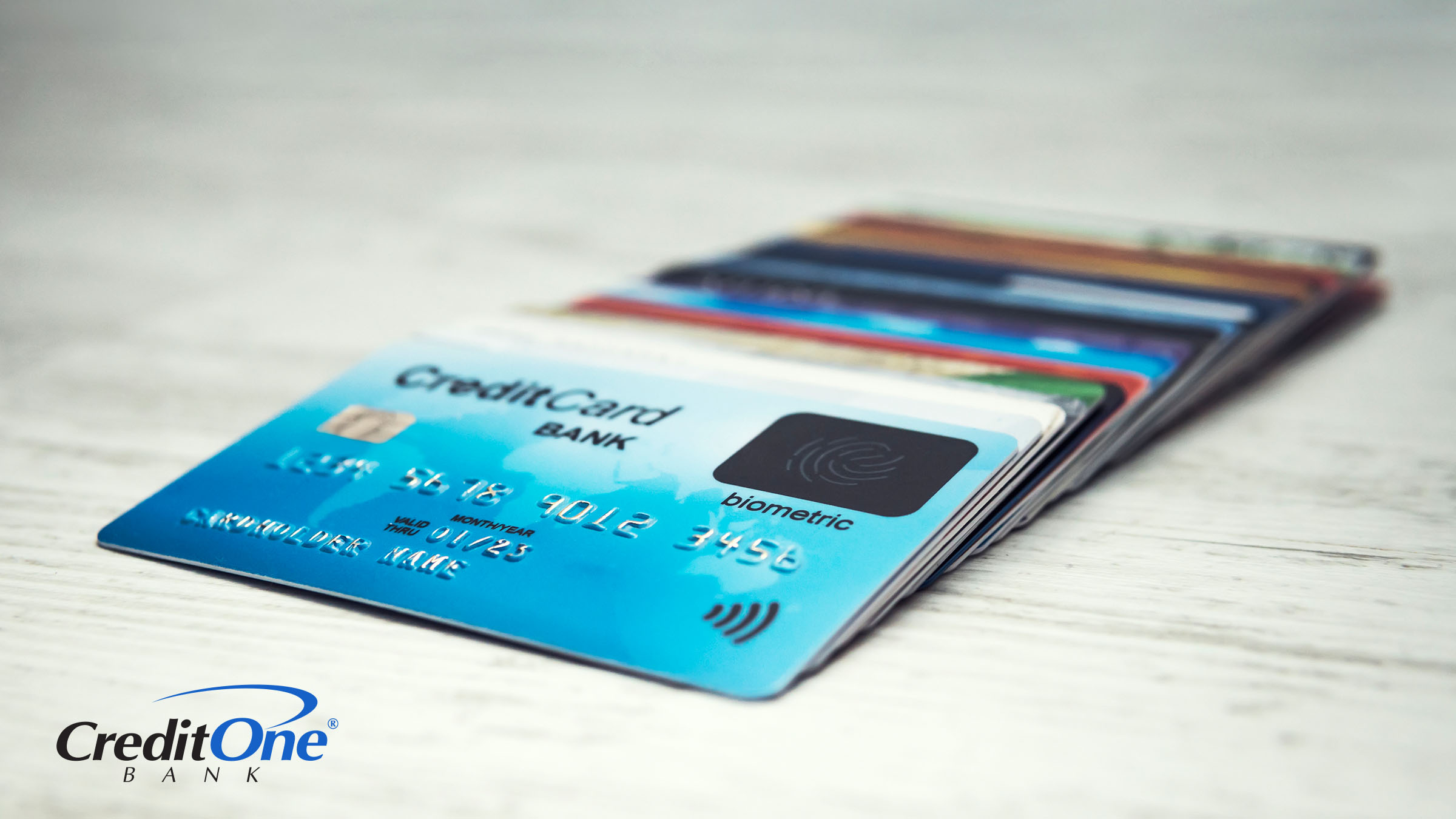 A fanned-out pile of payment cards sits on a table with a credit card on top of the rest, representing the benefits of using credit cards over other cards.