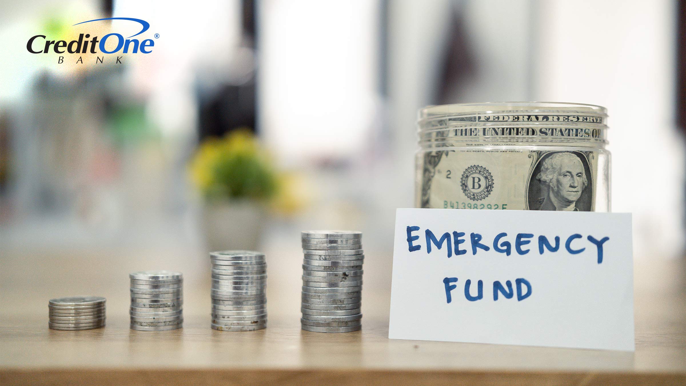Four stacks of coins, each larger than the last, lead up to a jar labeled “Emergency Fund” with paper bills inside. This represents how saving a little bit of money at a time can gradually grow into a healthy emergency fund.